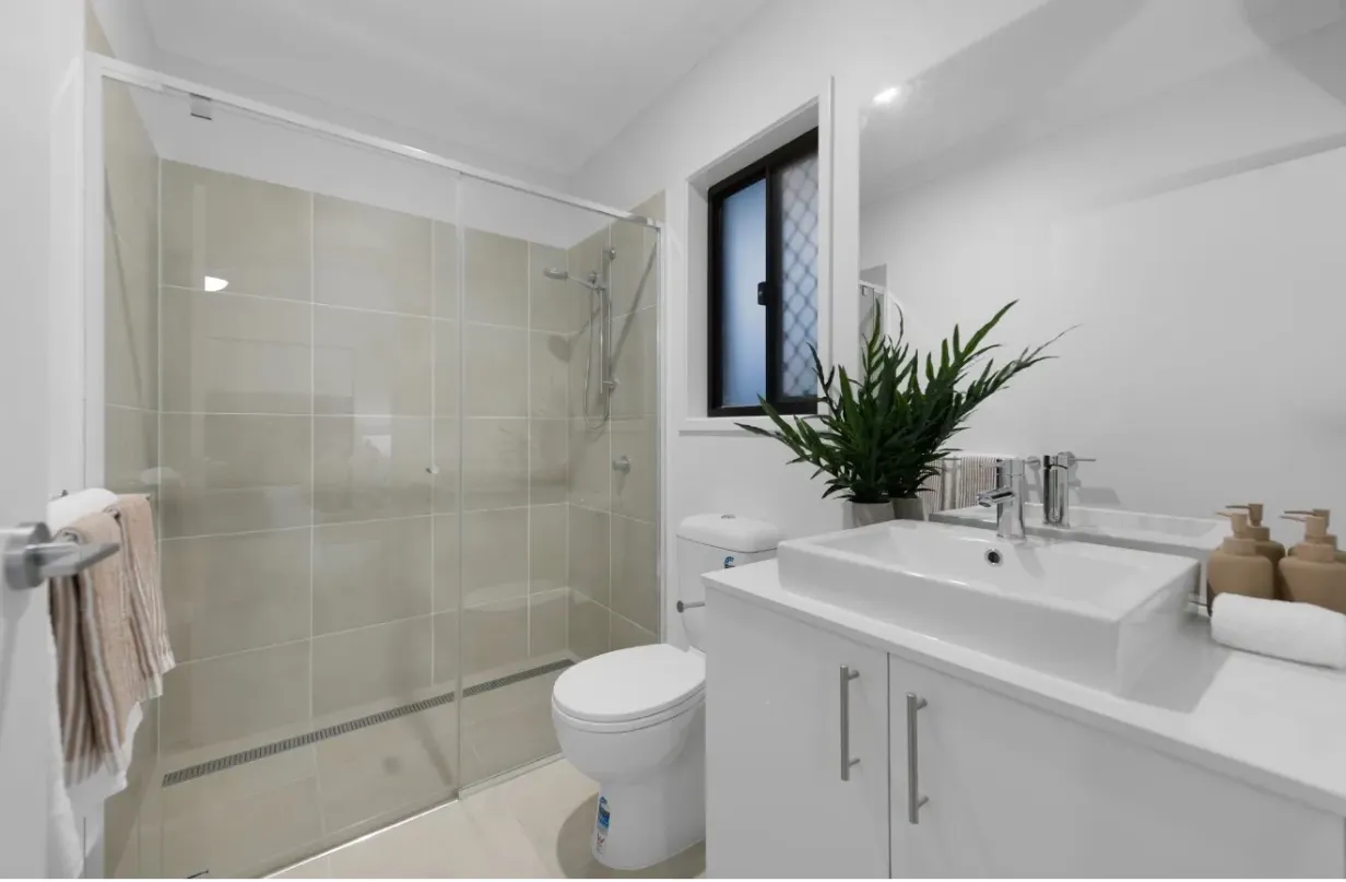 Bathroom with glass-enclosed shower, toilet and white vanity with single basin