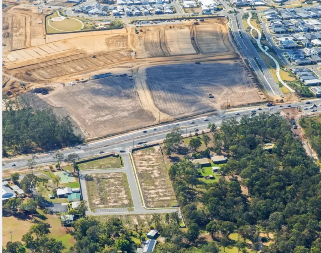 Aerial view over a Greenbank land estate with cleared house lots, earthworks and completed homes