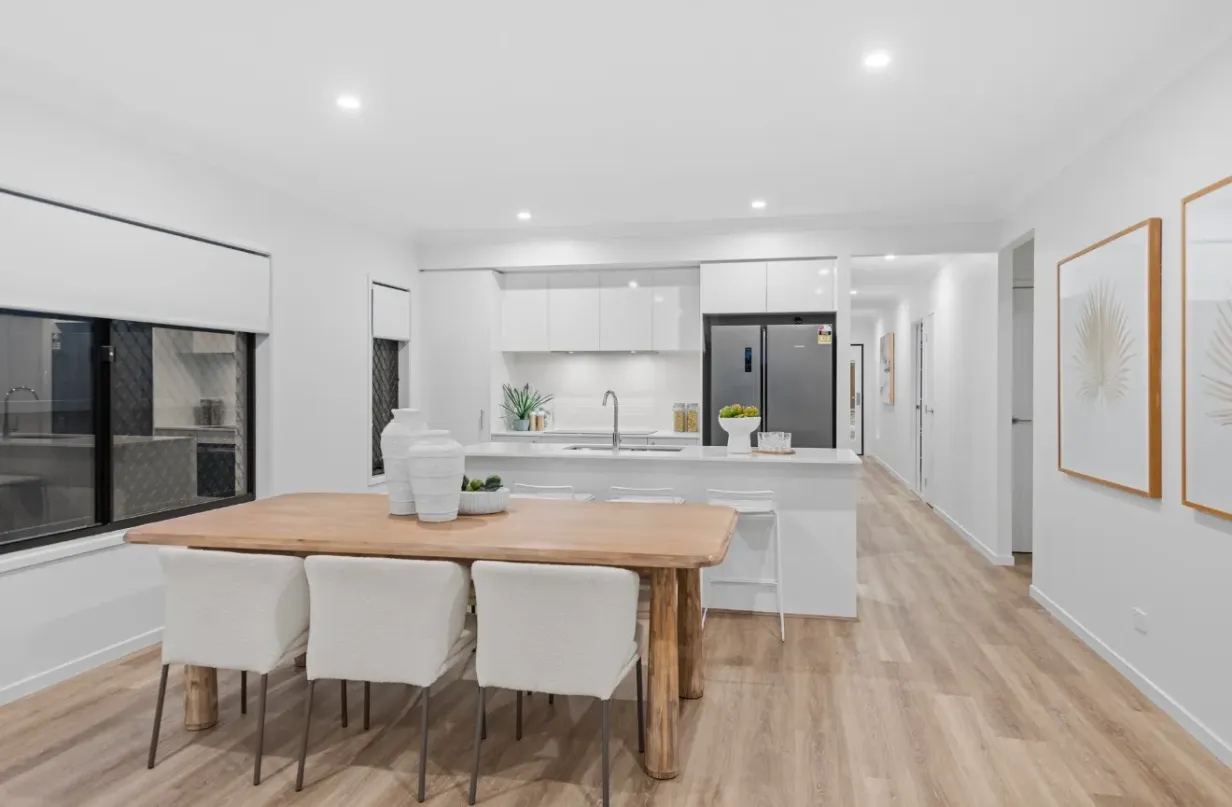 Open-plan kitchen, dining and living area with timber table and light timber-look flooring