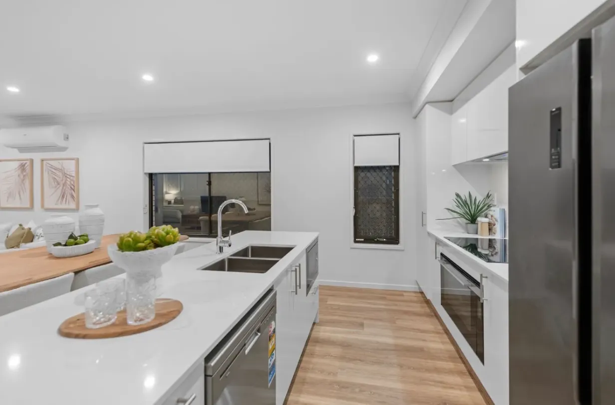 White kitchen with island bench, sink, stainless appliances and stone benchtop