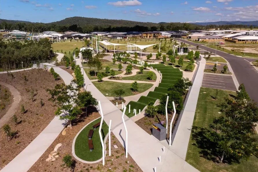 Aerial view of a landscaped community park with pathways, lawn areas and seating surrounded by new housing