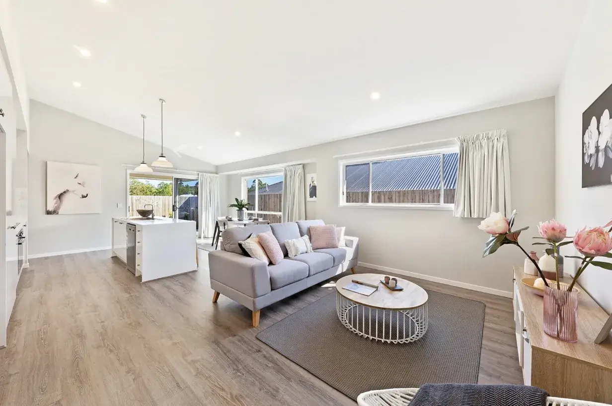 Open-plan living, kitchen and dining area with raked ceiling and timber-look flooring